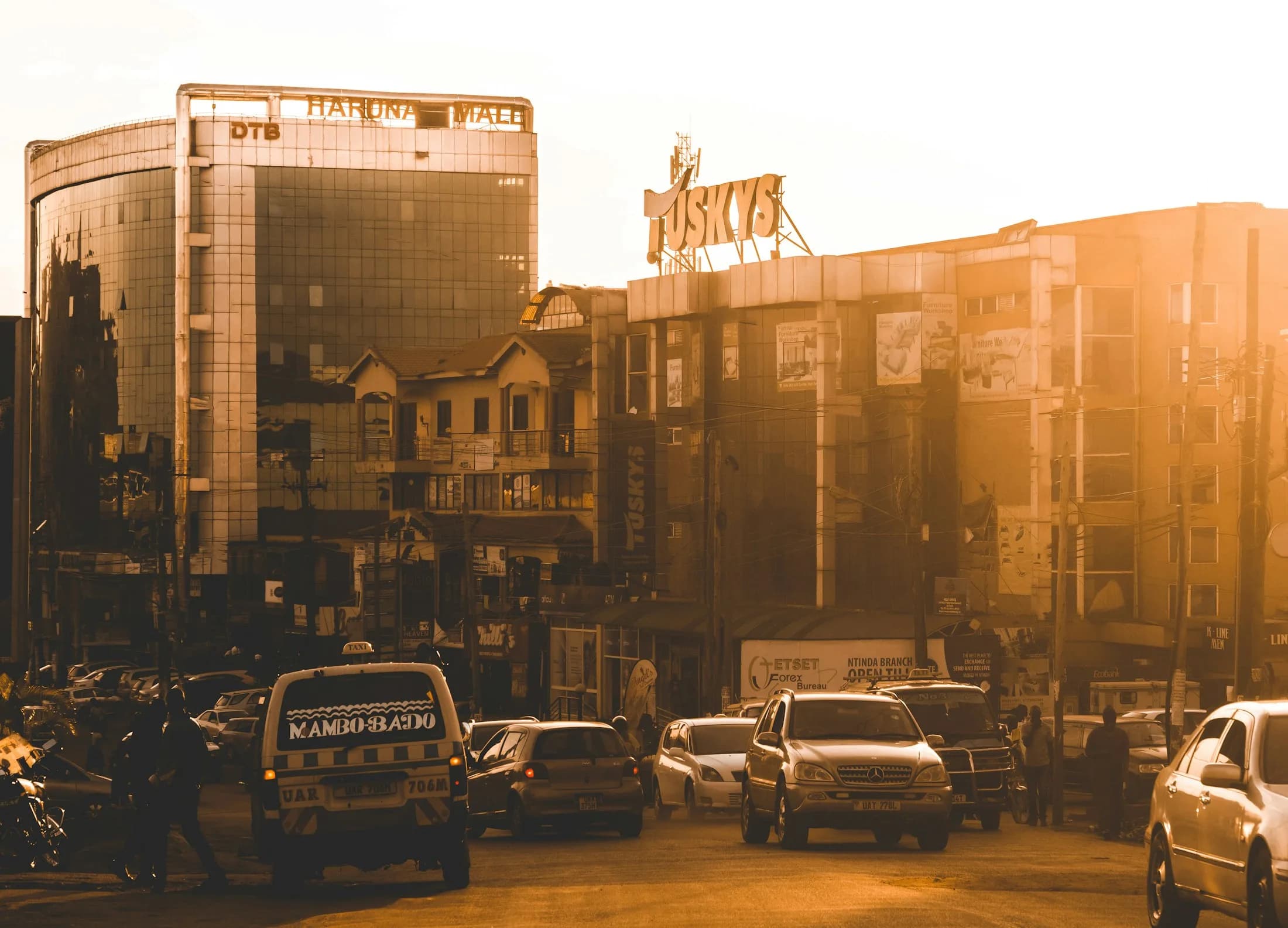 Busy Ugandan street at golden hour with buildings and traffic