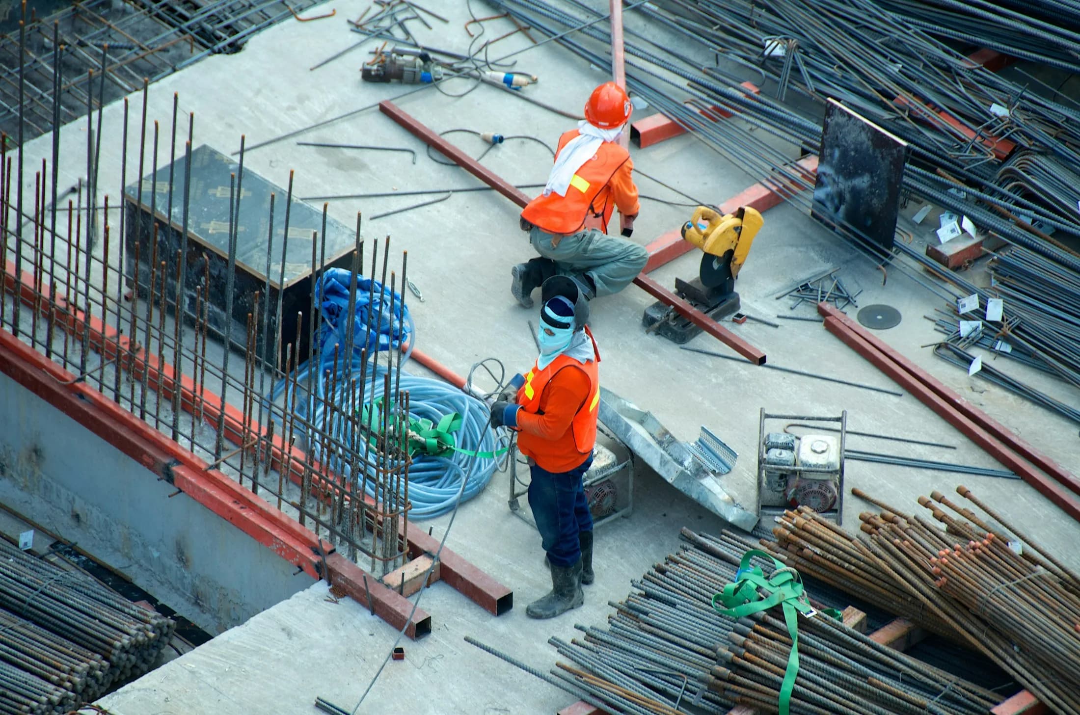 Construction workers in high-visibility vests fixing steel reinforcement on a concrete deck