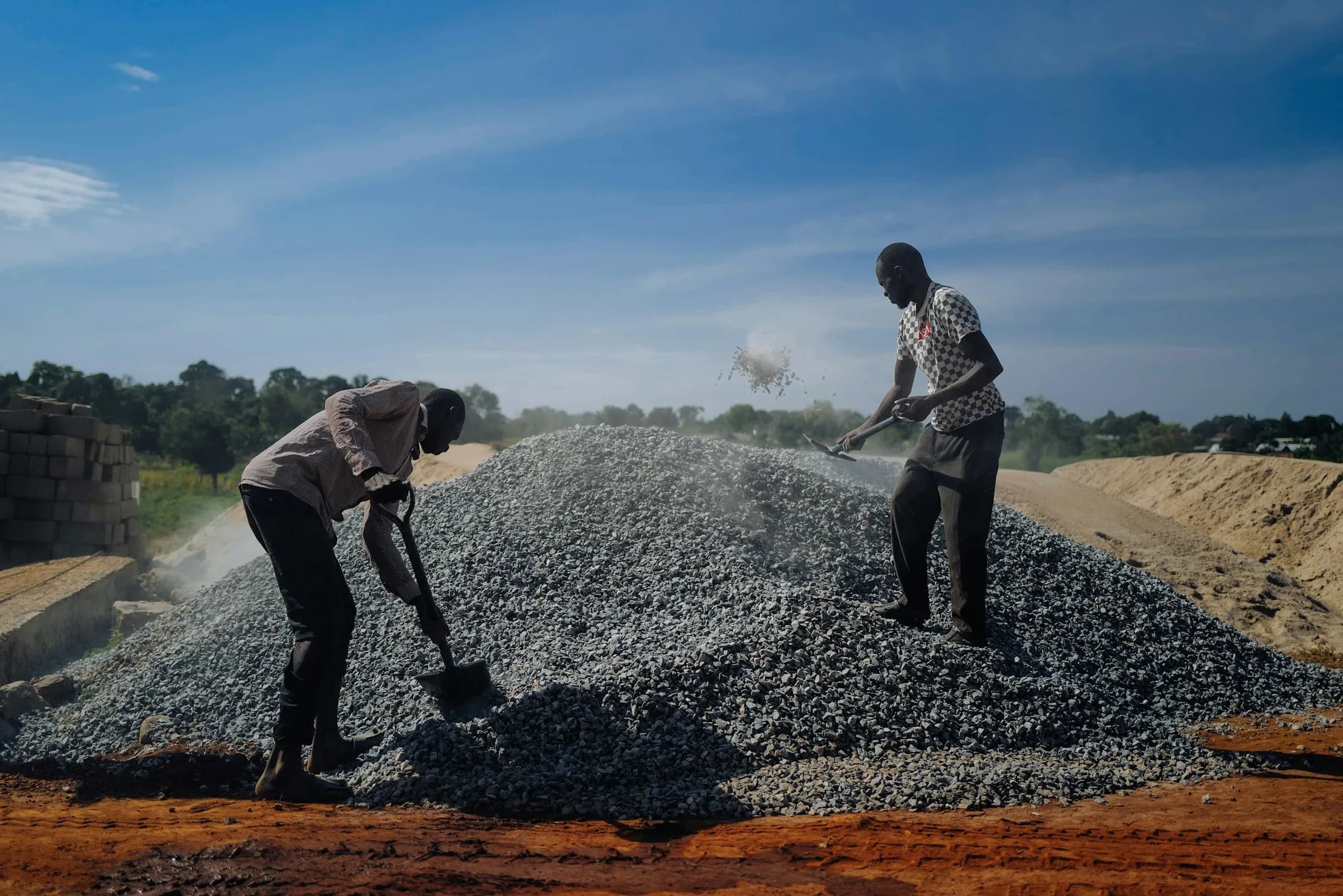 Construction workers spreading aggregate on a road project