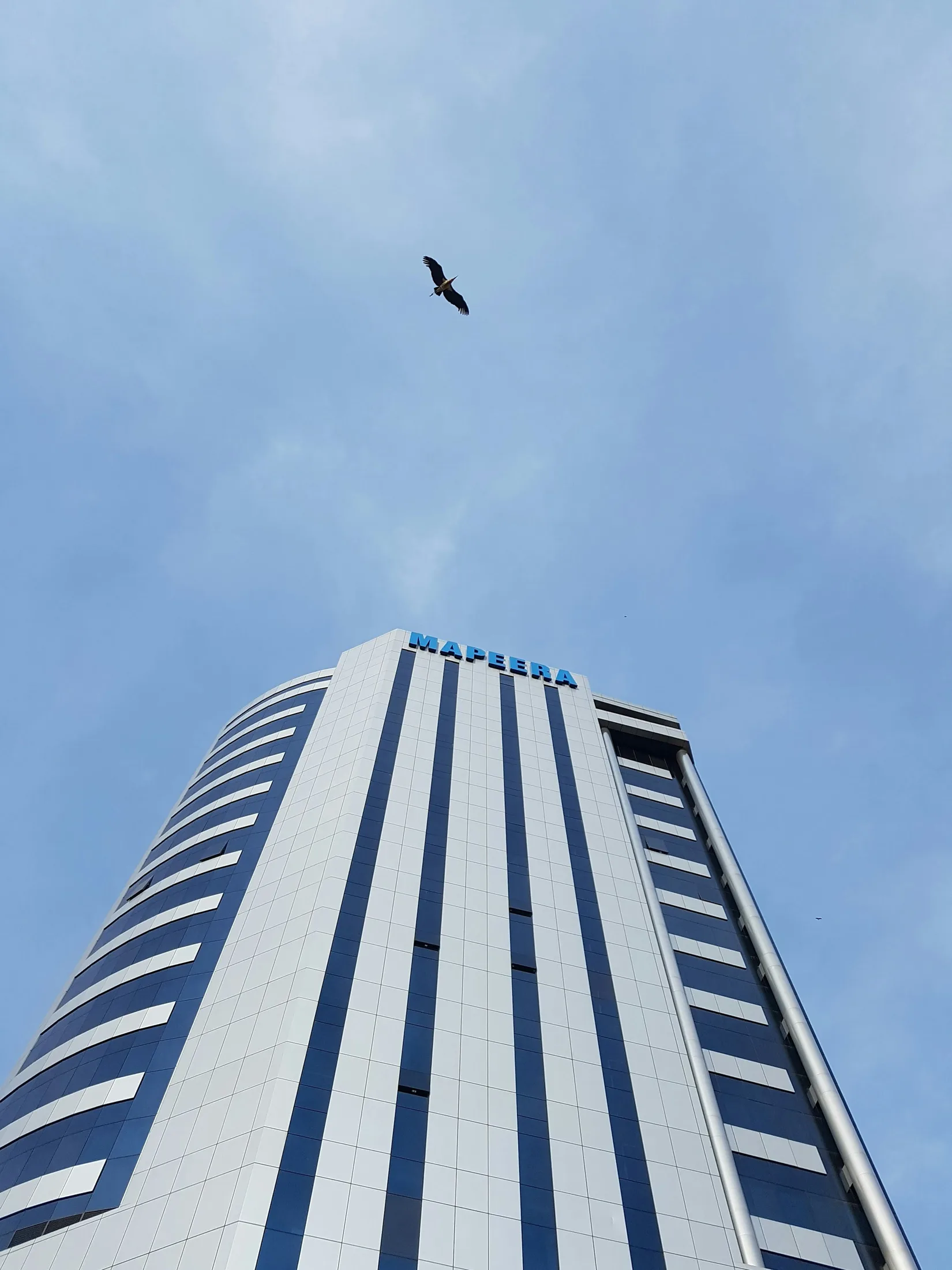 Pale modern office building against a blue Kampala sky